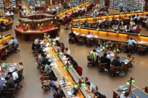 students in a university library sitting as desks studying.