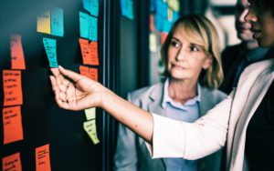 Two colleagues looking at post it notes on a board