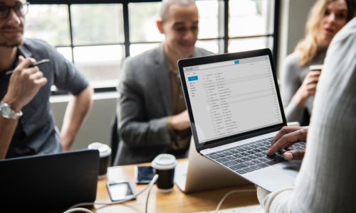 Four people discussing a topic with a laptop.